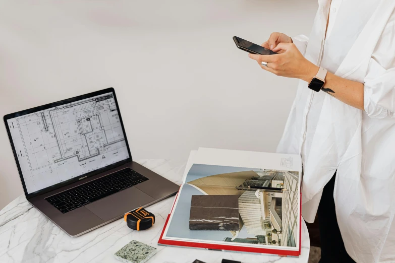 a woman holding a cell phone next to a laptop, a computer rendering, pexels contest winner, modernism, architectural plan, 🦑 design, product design shot, 2 0 0 0's photo