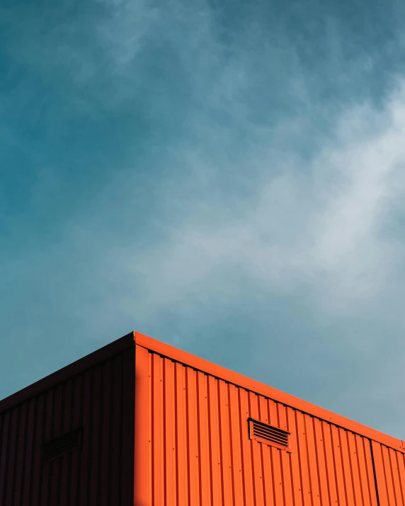 a red building with a blue sky in the background, a minimalist painting, pexels contest winner, galvalume metal roofing, shipping containers, orange gradient, black steel buildings