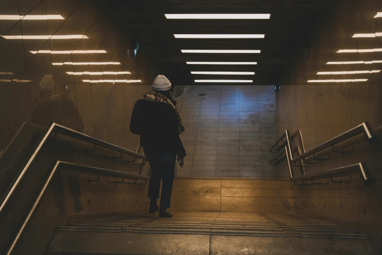 a person walking down a set of stairs, inspired by Elsa Bleda, pexels contest winner, happening, cyberpunk homeless, subway station, brown atmospheric lighting, people walking around