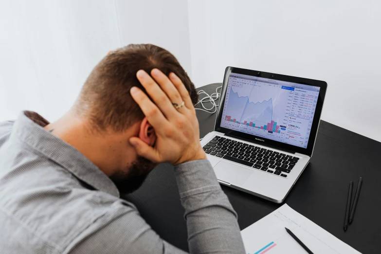 a man sitting at a desk with his head in his hands, pexels, charts, broken laptop screen, instagram post, ad image