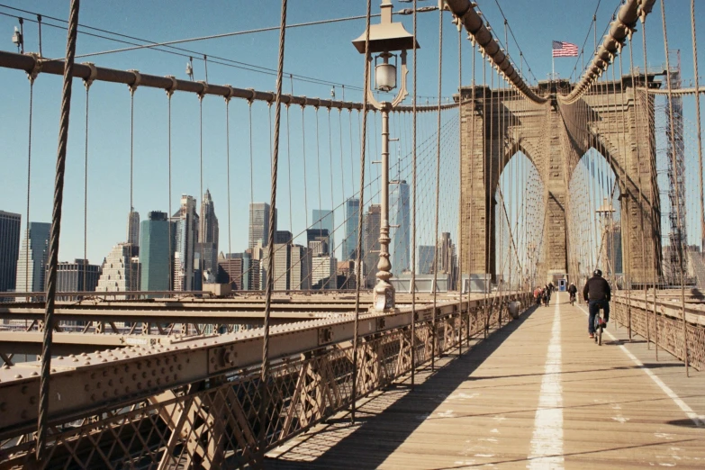 a person riding a bike across a bridge, pexels contest winner, art nouveau, streets of new york, panoramic anamorphic, webs, hustle and bustle