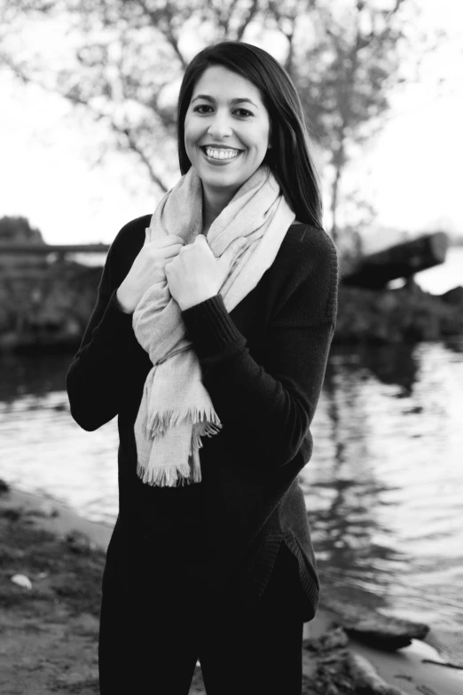 a woman standing next to a body of water, a black and white photo, beautiful smile, wrapped in a black scarf, female with long black hair, 15081959 21121991 01012000 4k