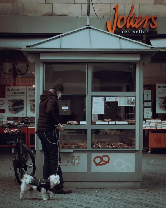 a man walking two dogs past a bakery on the street