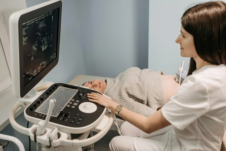 a woman laying on a bed in front of a monitor, by Adam Marczyński, pexels contest winner, medical machinery, membrane pregnancy sac, upper body image, with a stethoscope