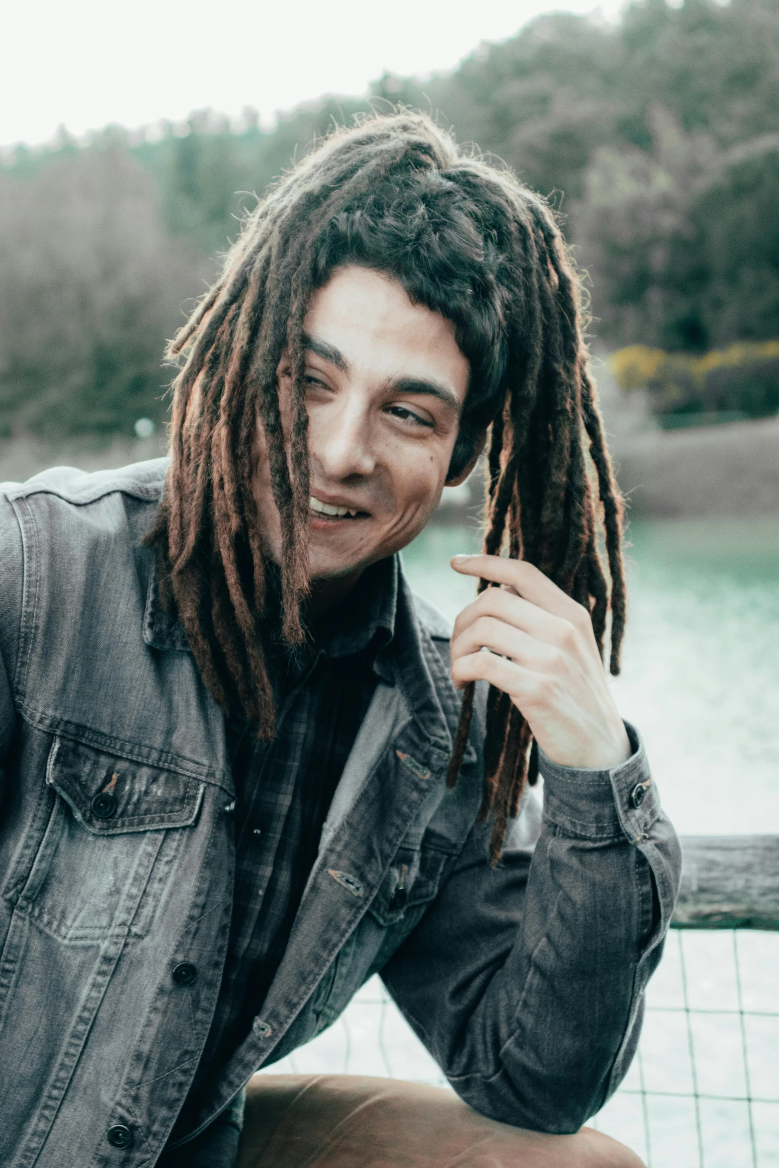 a person with dreadlocks posing near the water