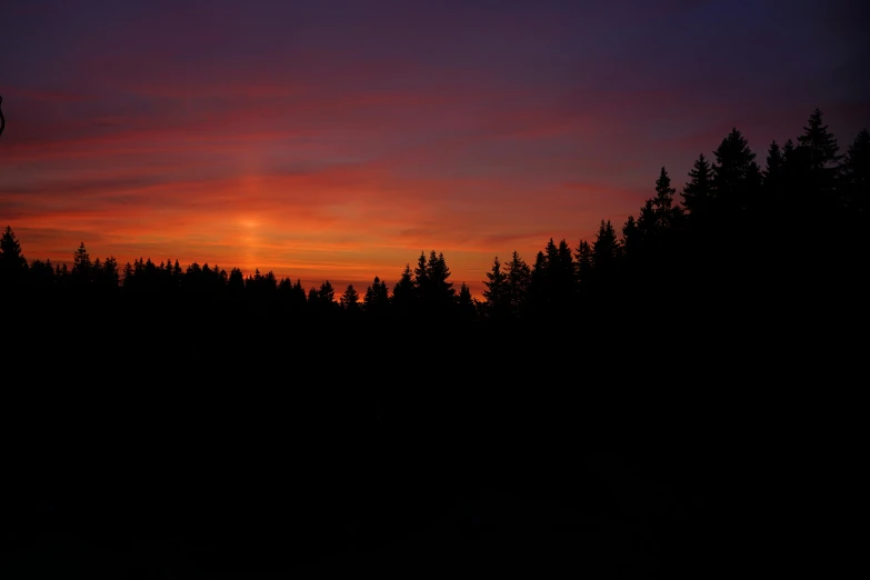 a sunset view of trees near to some hills