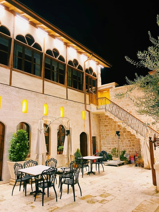 a building with tables and chairs outside at night, les nabis, adar darnov, patio