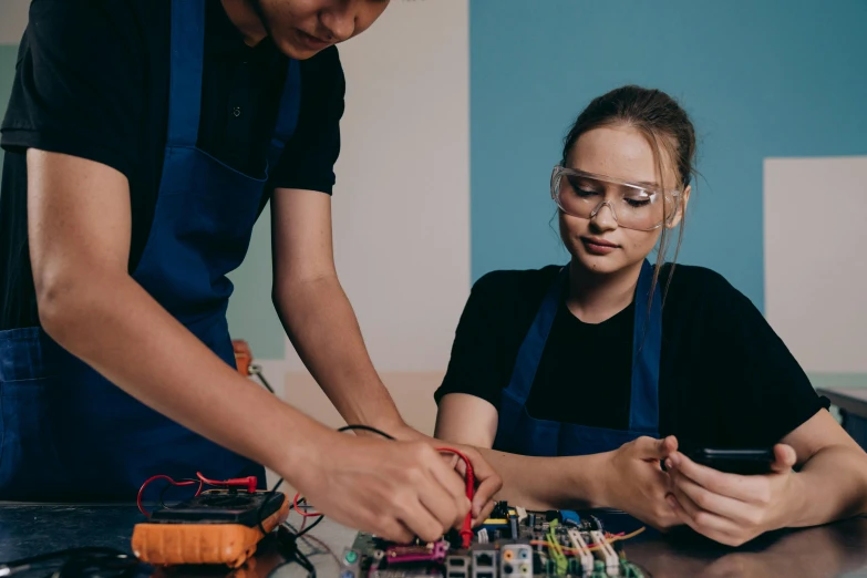 a couple of people that are working on some electronics, a portrait, trending on pexels, aged 13, school curriculum expert, avatar image