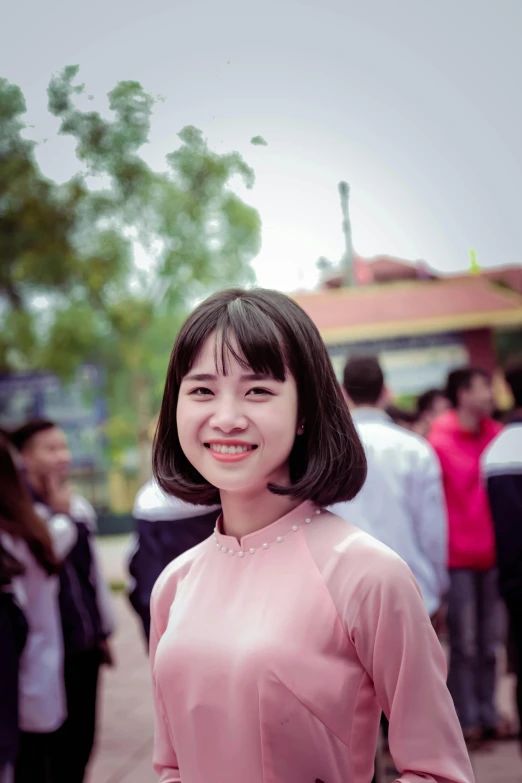 a woman standing in front of a crowd of people, a picture, inspired by Ruth Jên, slight cute smile, headshot profile picture, 21 years old, square