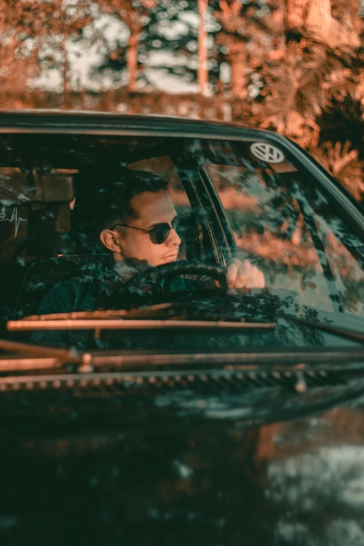 a man sitting in the driver's seat of a car, by Adam Marczyński, pexels contest winner, shady look, profile image, sunfaded, a man wearing a black jacket