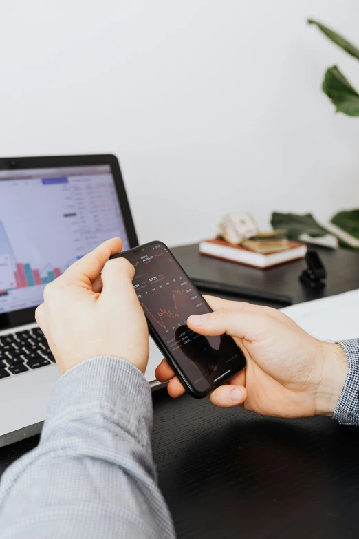 a person holding a cell phone in front of a laptop