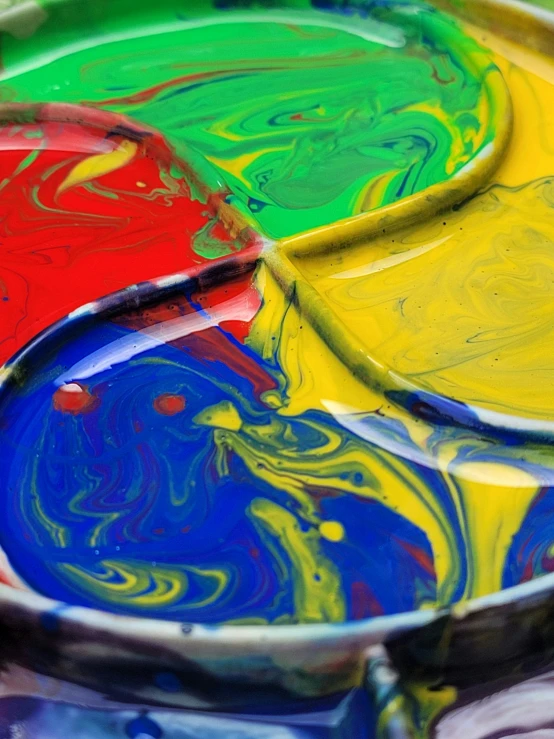 a bowl filled with paint sitting on top of a table, inspired by Sam Francis, trending on unsplash, action painting, primary colors, swirly, rainbow liquids, “ painting