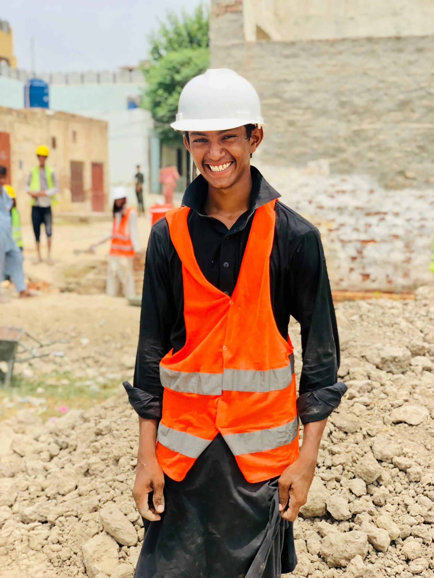 a man standing on top of a pile of dirt, smiling for the camera, worksafe. instagram photo, bangladesh, wearing a fancy dress