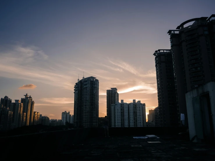 city buildings are silhouetted against an evening sky