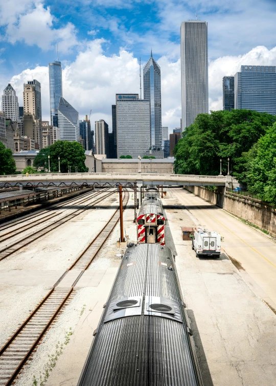 a large long train on a steel track, by Joe Stefanelli, pexels contest winner, chicago skyline, train station in summer, uncropped, high quality product image”