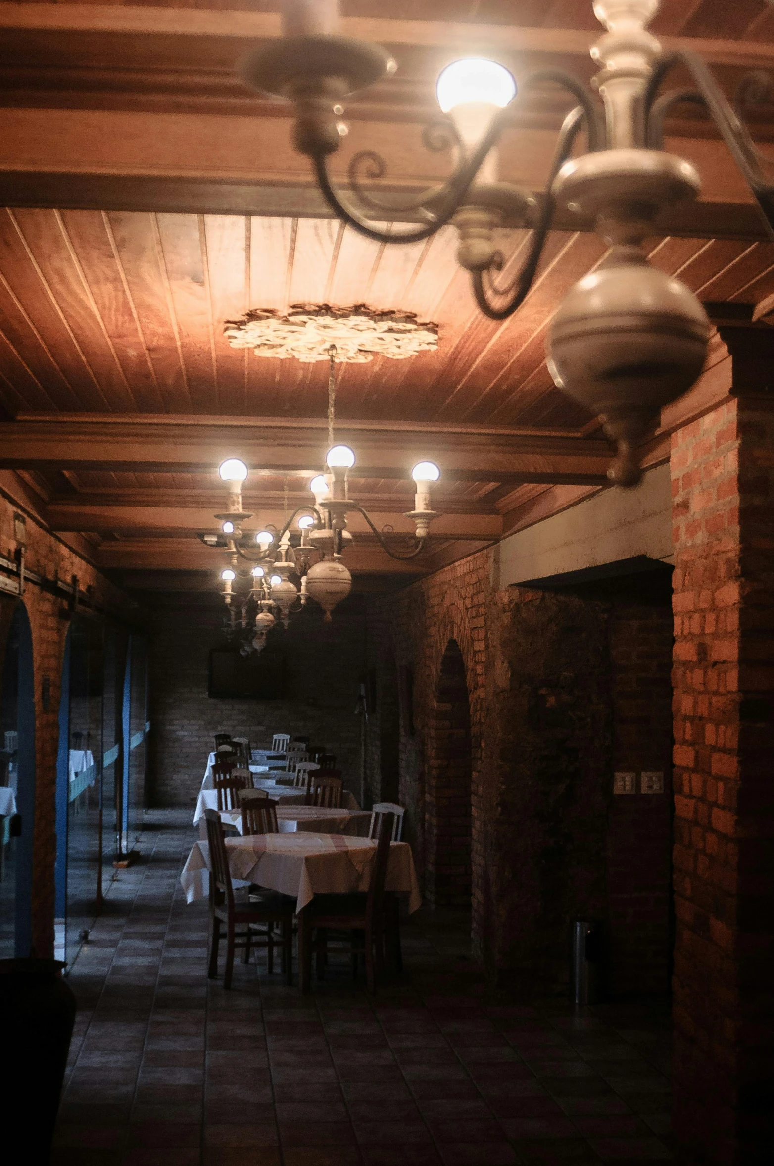 a long dining room with a chandelier hanging from the ceiling, by Daniel Lieske, unsplash, dimly-lit cozy tavern, 2 5 6 x 2 5 6 pixels, orthodox, cellar