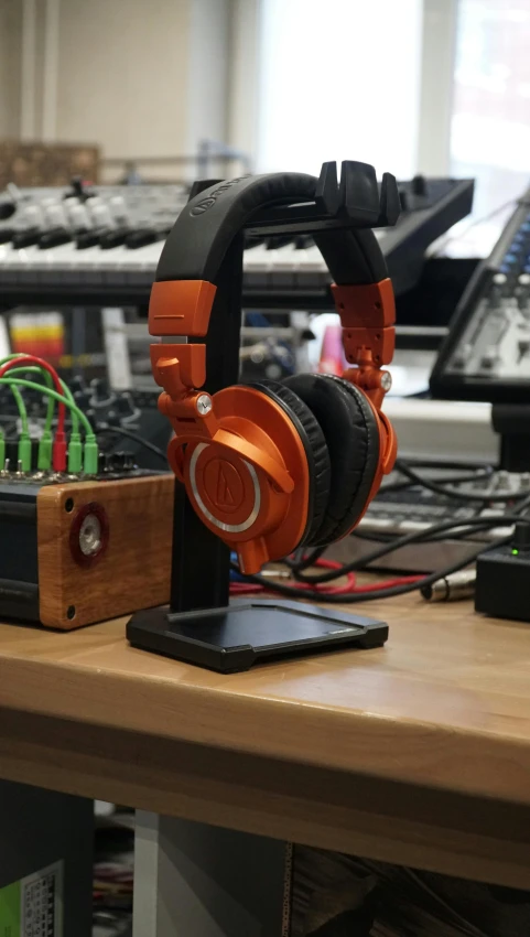 a pair of headphones sitting on top of a wooden desk, private press, on a advanced lab, orange metal ears, thumbnail, synth