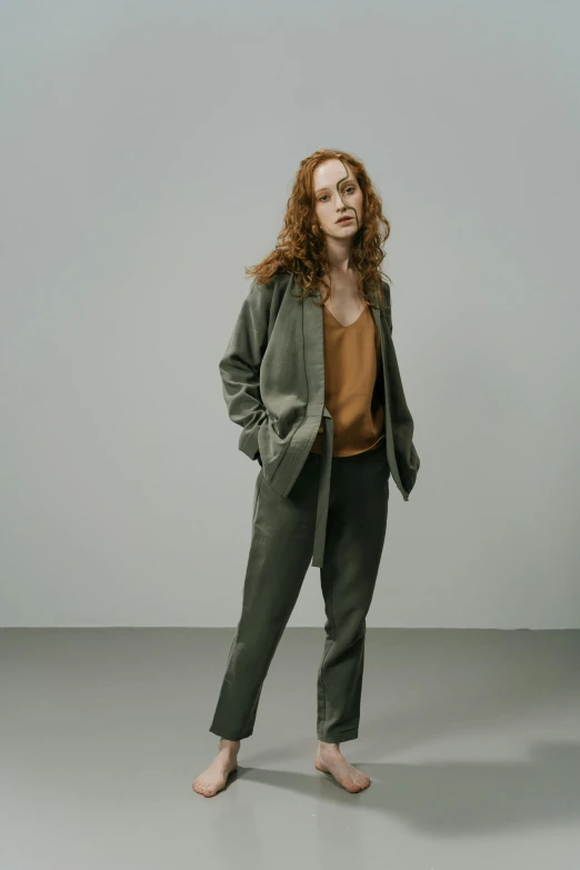 a woman in a green jacket is standing on a gray surface