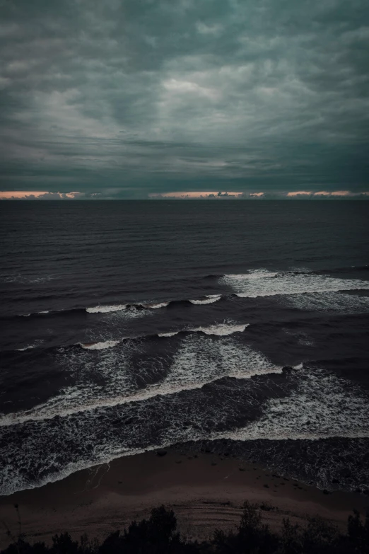 a large body of water under a cloudy sky, an album cover, unsplash contest winner, chilly dark mood, coastline, shot from above, high quality photo