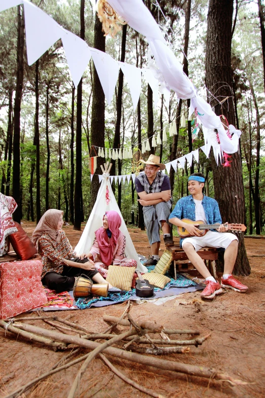 a group of people sitting around a tent in the woods, an album cover, by Basuki Abdullah, sumatraism, forest style studio shot, holiday, roaming entertainers, islamic