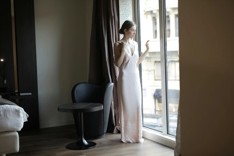 a woman standing in front of a window looking out at the street