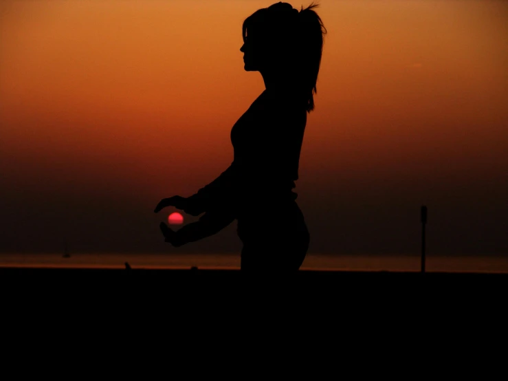 a silhouette of a woman holding a frisbee at sunset, by Eglon van der Neer, art photography, glass ball at the waist, red orange lighting, profile pic, medium-shot