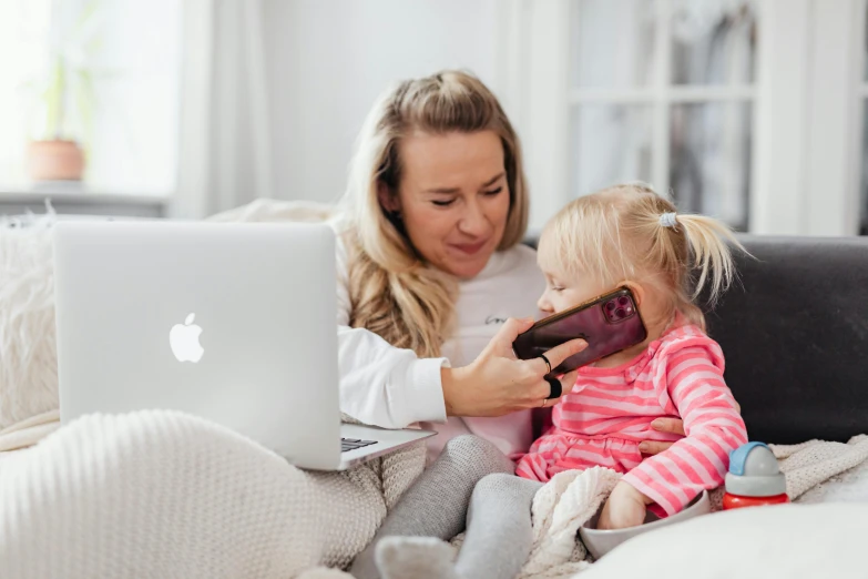 a woman sitting on a couch holding a little girl, pexels contest winner, coding time, avatar image, iphone, 1 4 9 3