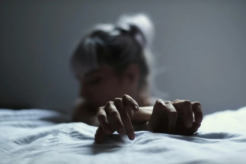 a close up of a person's hands on a bed, a photo, trending on pexels, antipodeans, feral languid woman, lying on an empty, midnight, worried