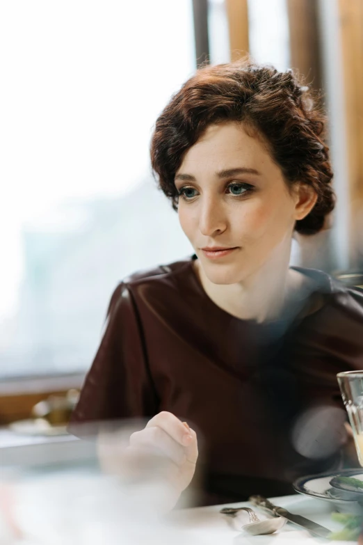 a woman looks intently into the distance as she sits at a table