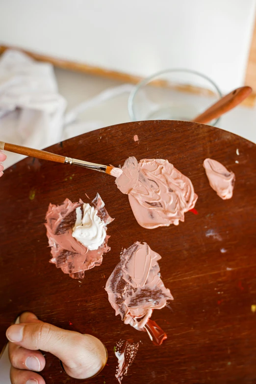 a close up of a person holding a paintbrush, inspired by Adélaïde Labille-Guiard, trending on pexels, arbeitsrat für kunst, brown and pink color scheme, white paint, melted paint, a wooden