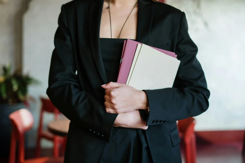 a woman in a black suit holding a book, unsplash, three piece suit, holding a stuff, lawyer clothing, server in the middle