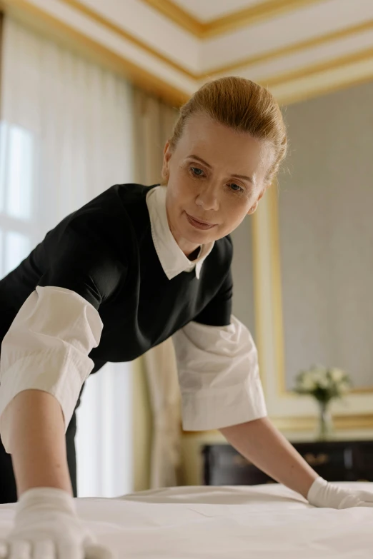 a woman dressed in an old fashioned dress and gloves stretching on a bed