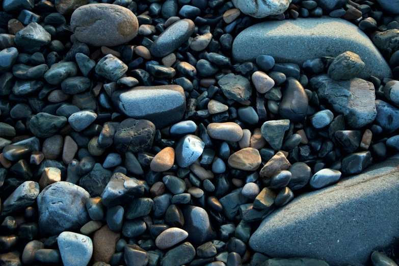 a pile of rocks sitting on top of a beach, an album cover, by Jan Rustem, unsplash, zoomed in, ((rocks)), patterns and textures, evening lighting