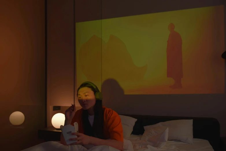 a woman sitting on top of a bed next to a lamp, a hologram, inspired by Yoshio Markino, unsplash, video art, breakfast, wearing a noh theatre mask, ambient amber light, capsule hotel