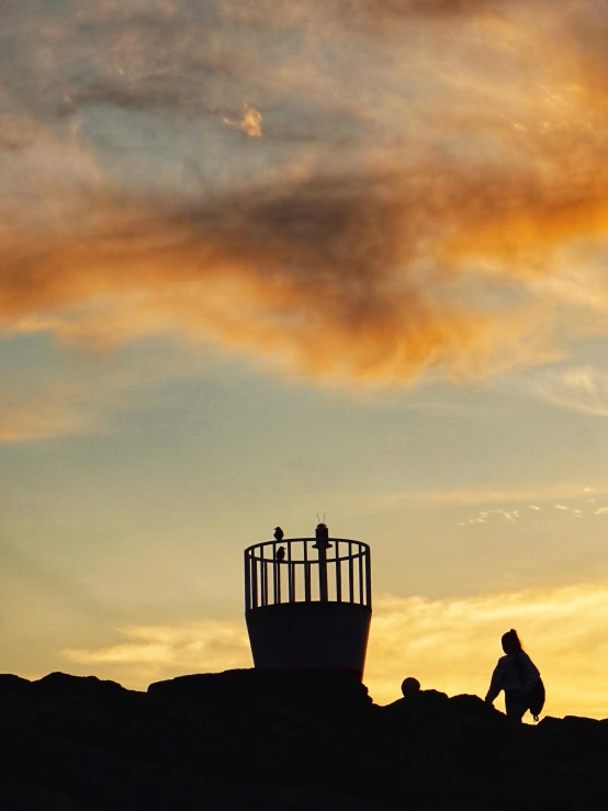 two men on the top of a mountain looking up at an object