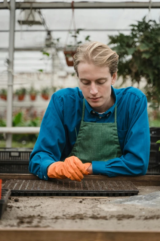 a woman in an apron working in a greenhouse, a portrait, unsplash, arbeitsrat für kunst, very handsome, blue gloves, thumbnail, smooth in _ the background