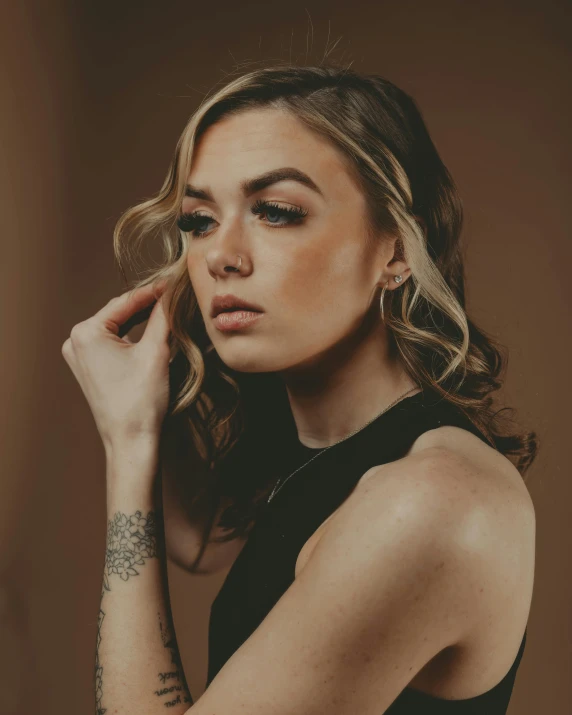 a woman in a black dress posing for a picture, an album cover, inspired by Elsa Bleda, trending on pexels, antipodeans, her skin is light brown, sydney sweeney, prideful look, with tattoos