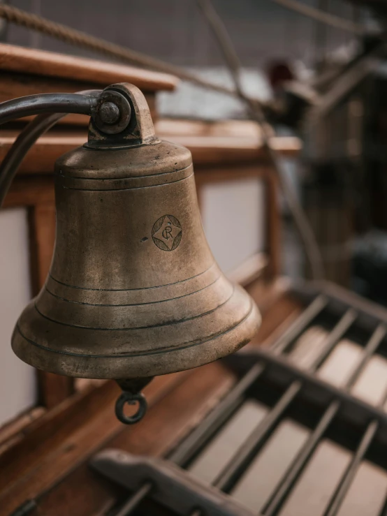 a bell hanging from the side of a ship, by Christopher Wren, trending on pexels, arts and crafts movement, faded and dusty, located in a wizard's shop, up close image, tall