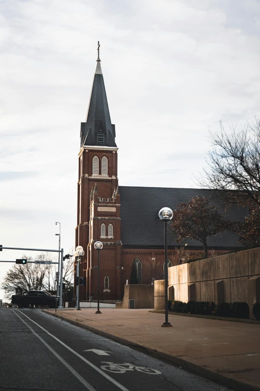 an empty street with a church in the background, by Jacob Burck, unsplash, bentonville arkansas, multiple stories, taken with sony alpha 9, exterior view