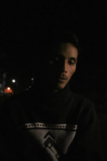 a man looking at his cell phone in the dark, an album cover, reddit, he is wearing a brown sweater, mohamed chahin, portrait mode photo, ( ( theatrical ) )