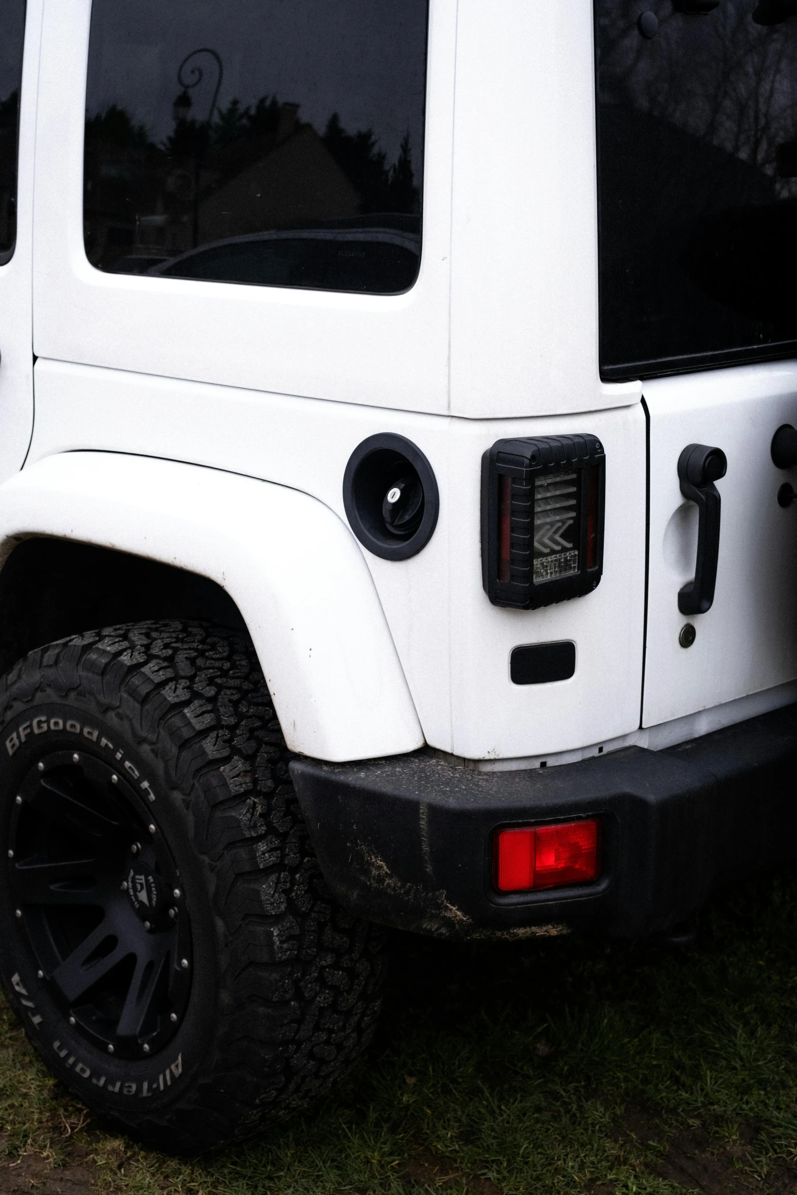 the white jeep with the black wheels is parked on grass