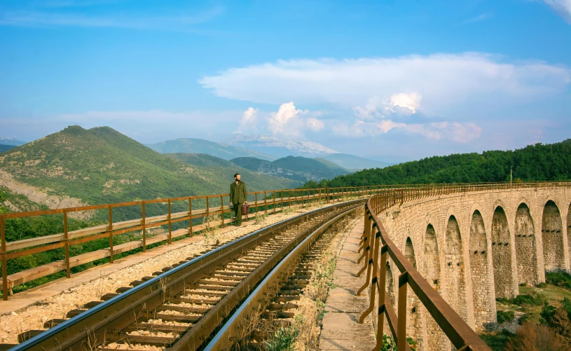 a man standing on top of a train track, by Julia Pishtar, pexels contest winner, romanticism, mediterranean vista, aqueducts, carpathian mountains, blonde