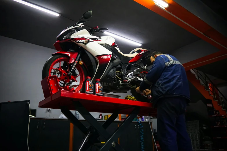 a man working on a motorcycle in a garage, by Alejandro Obregón, pexels contest winner, white red, avatar image, gtr xu1, profile picture