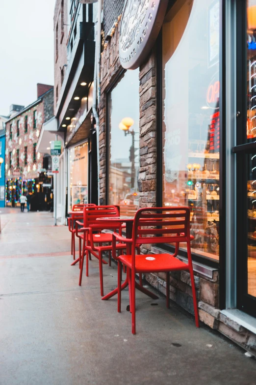 a sidewalk with red chairs, and a clock displayed