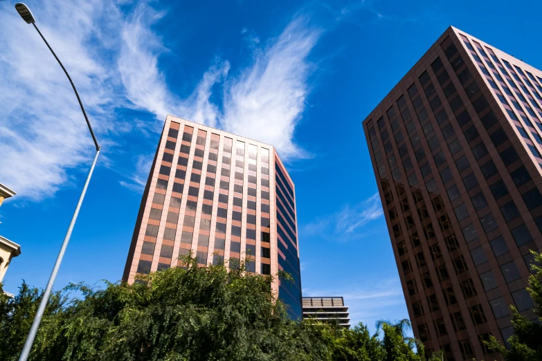 a couple of tall buildings sitting next to each other, phoenix, cupertino, orange and blue sky, 3 - piece