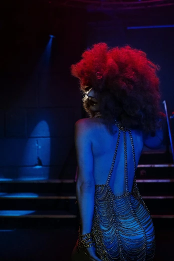 a woman in red wig standing in front of a stage