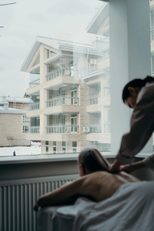 a woman laying in bed looking out the window