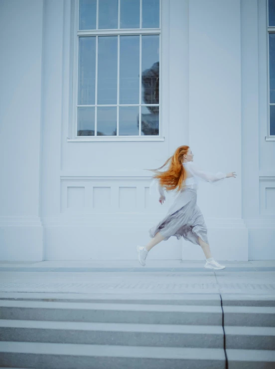 a woman running down a set of stairs, by Grace Polit, pexels contest winner, magical realism, long orange hair floating on air, white building, dancing gracefully, near a window