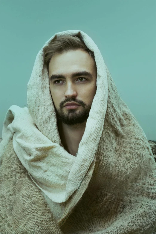 a bearded man wrapped in a beige towel