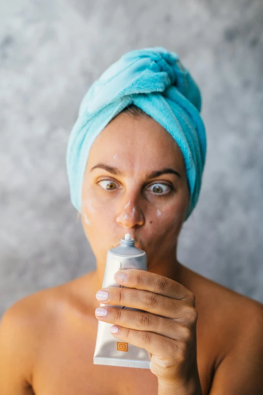 a woman with a towel on her head brushing her teeth, by Drew Tucker, spraying liquid, defined face, slightly tanned, silicone skin